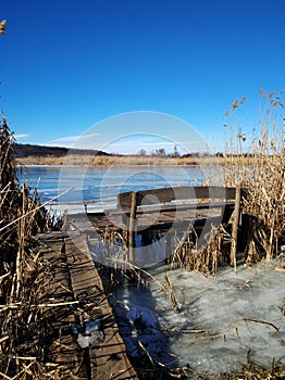 Winter river bank. Frozen water, a pier for fishing