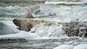 Winter river flowing near snow and ice covered stones, slow motion video detail