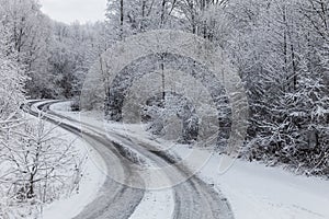 Winter road through icy forest covered in snow after ice storm and snowfall