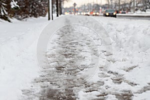 Winter road with melting from salt snow. Close up of sidewalk with slush on snowy day