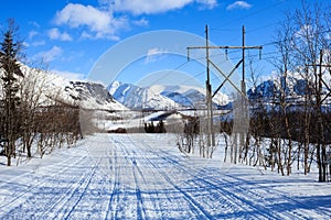 Winter road in the polar mountains and old electricity pillars
