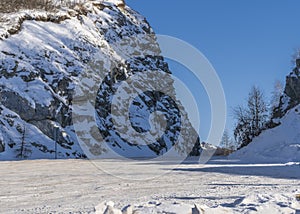 The winter road runs between steep cliffs.