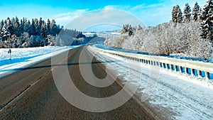 winter road trip: asphalt road through snowy forest and scenic snowy landscape with trees in the woods