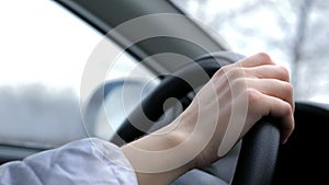 Winter road trip. Profile of a young beautiful girl driver in a jacket and hat, driving a car. A traveling girl. Happy