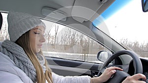 Winter road trip. Profile of a young female driver, a young blonde driving a car. Side view. A traveling girl. Portrait