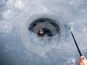 Winter rod on blue ice. Winter fishing background. Fishing rod and ice hole