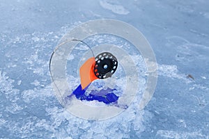 Winter rod on blue ice. Winter fishing background. Fishing rod and ice hole on frozen about