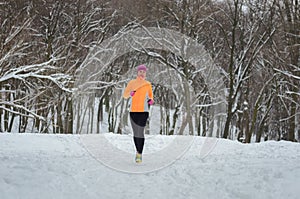 Winter running in forest: happy woman runner jogging in snow, outdoor sport