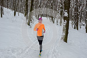 Winter running in forest: happy woman runner jogging in snow, outdoor sport