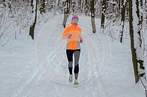 Winter running in forest: happy woman runner jogging in snow, outdoor sport