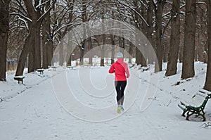 Winter running in park: happy active woman runner jogging in snow, outdoor sport and fitness