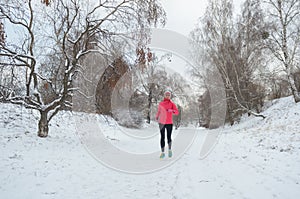 Winter running in park: happy active woman runner jogging in snow, outdoor sport and fitness