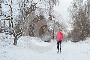 Winter running in park: happy active woman runner jogging in snow, outdoor sport and fitness