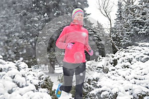 Winter running in park: happy active woman runner jogging in snow, outdoor sport and fitness