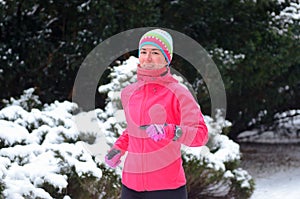 Winter running in park: happy woman runner jogging in snow, outdoor sport