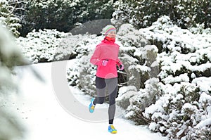 Winter running in park: happy woman runner jogging in snow, outdoor sport and fitness