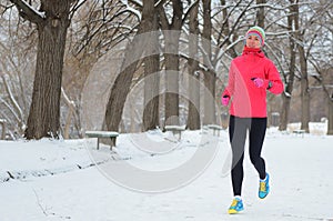 Winter running in park: happy woman runner jogging in snow, outdoor sport and fitness