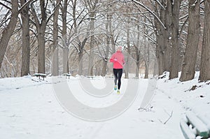 Winter running in park: happy woman runner jogging in snow, outdoor sport and fitness