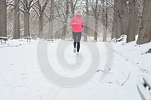 Winter running in park: happy woman runner jogging in snow, outdoor sport and fitness