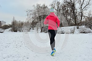 Winter running in park: happy woman runner jogging in snow, outdoor sport and fitness