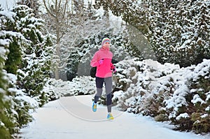 Winter running in park: happy woman runner jogging in snow, outdoor sport and fitness