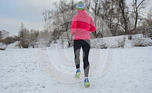 Winter running in park: happy woman runner jogging in snow, outdoor sport and fitness