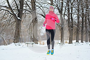 Winter running in park: happy woman runner jogging in snow, outdoor sport and fitness