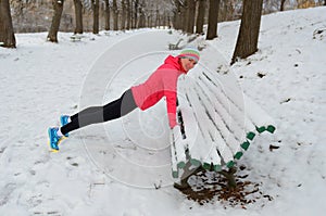 Winter running in park: happy woman runner warming up and exercising before jogging in snow