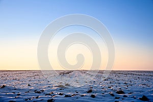 Winter rural landscape, a snowy agricultural field covered with snow and ice, at sunset, in the Banat region of Vojvodina, Serbia