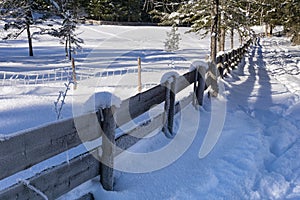 Winter rural landscape with wooden fence covered with snow
