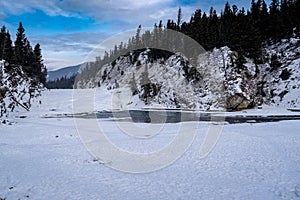 Winter scene of Bow Falls in Banff National Park with an open river, snow and ice