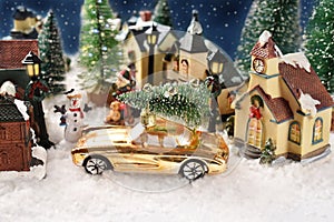 Winter scene decoration with houses in small town on Christmas night with a yellow car with a Christmas tree on the