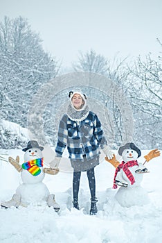 Winter scene with happy people on white snow background. Winter day. Winter woman clothes. Cute snowman at a snowy