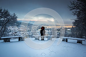 Winter Scene with A Lone Man Sitting on Snowy Benches Overlooking Bergen City Center in A Storm