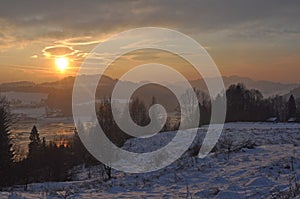 Winter scene with mountains, trees, sunset and snow