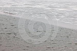 Winter scene showing thin ice and fresh snow at the side of a fast flowing river, danger in spring