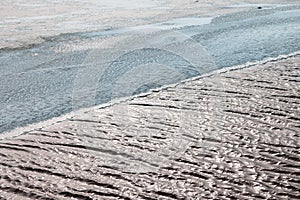 Winter scene showing thin ice and fresh snow at the side of a fast flowing river, danger in spring