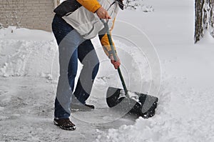 Winter scene - a tall Caucasian man shovels a driveway in a residential area in Ontario Canada