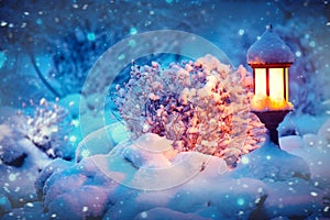 Winter scene. Xmas Decoration with a lantern on snow in a winter garden. Christmas Background. Lamp at night