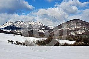 Sunny winter mountain landscape with big rock , beautiful blue sky, white clouds.