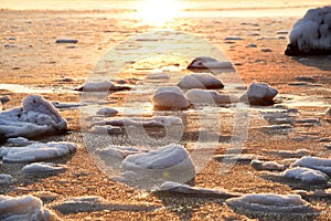 Winter sea in the early morning. frozen water and stones at dawn.