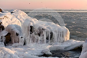 Winter sea in the early morning. frozen water and stones at dawn.