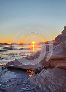 Winter sea sunset. Panoramic view of the snow-covered shore of the frozen sea, the lake at sunset. Shards of ice close-up.