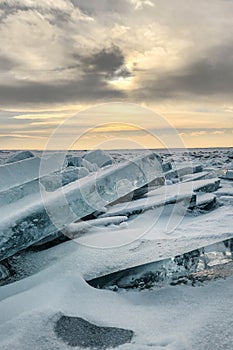 Winter sea sunset. Panoramic view of the snow-covered shore of the frozen sea, the lake at sunset. Shards of ice close-up.