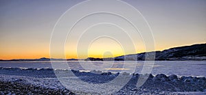 Winter sea sunset. Panoramic view of the snow-covered shore of the frozen sea, the lake at sunset. Shards of ice close-up.