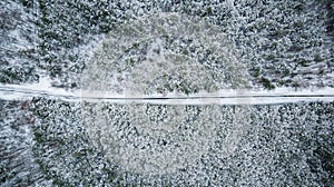 Winter season aerial top down view of a straight line road in forest