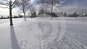 Winter season background. Public park with snow-covered footpath on a winter day.