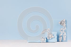 Winter season elegant cold background for advertising and design - pastel blue gift boxes with silver sparkles ribbons, bow.