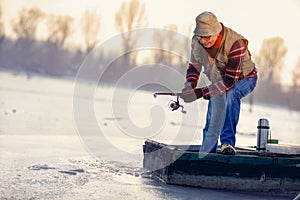 Winter season - fisherman fishing on the frozen lake