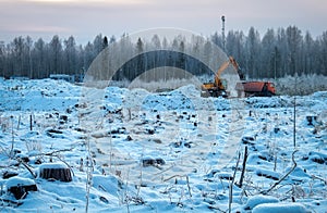 Winter season. Forest in snow. Excavator and truck